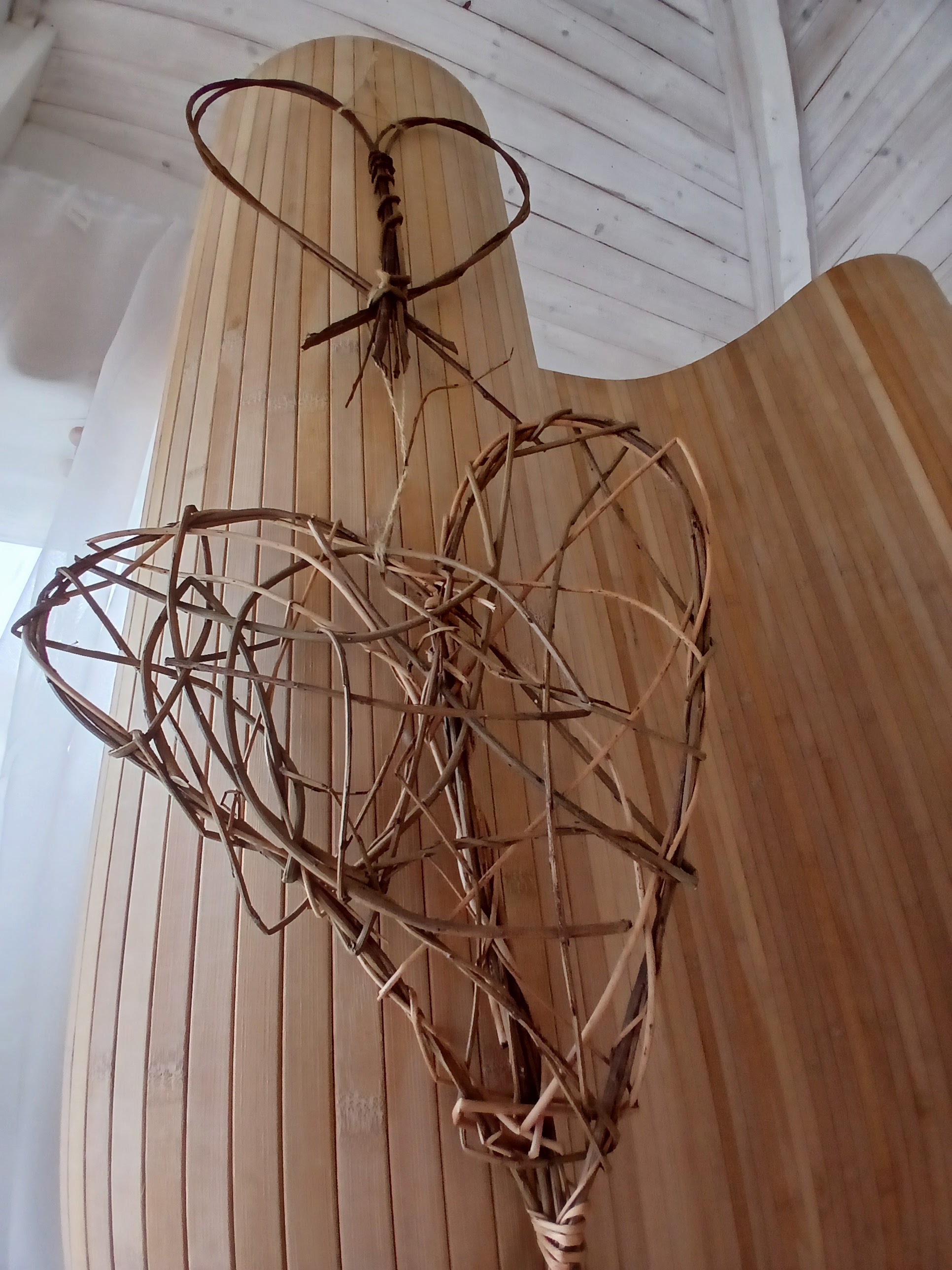 Two woven willow hearts hanging on a bamboo screen in the treatment room