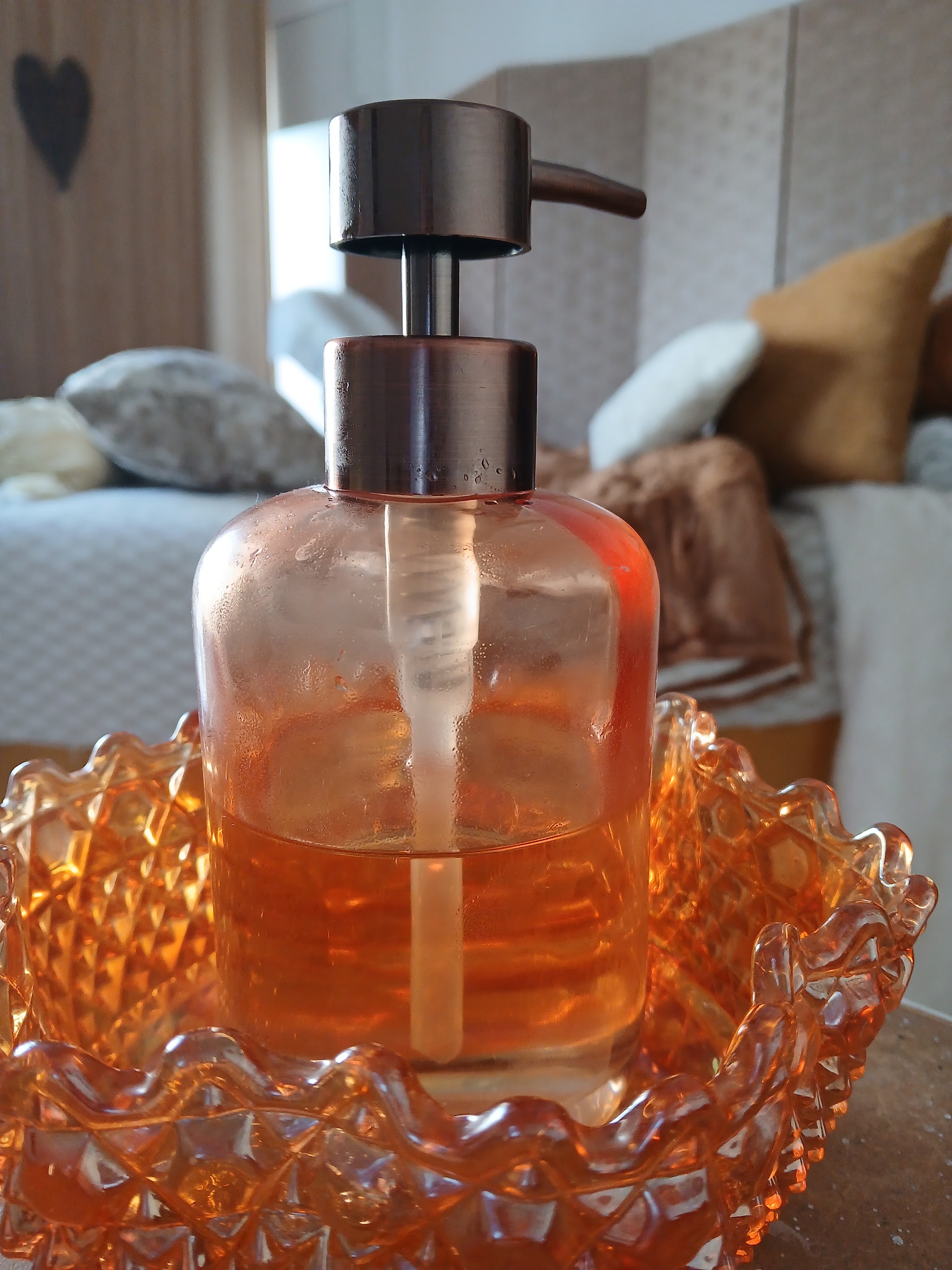 An amber glass oil dispenser in a cut glass dish