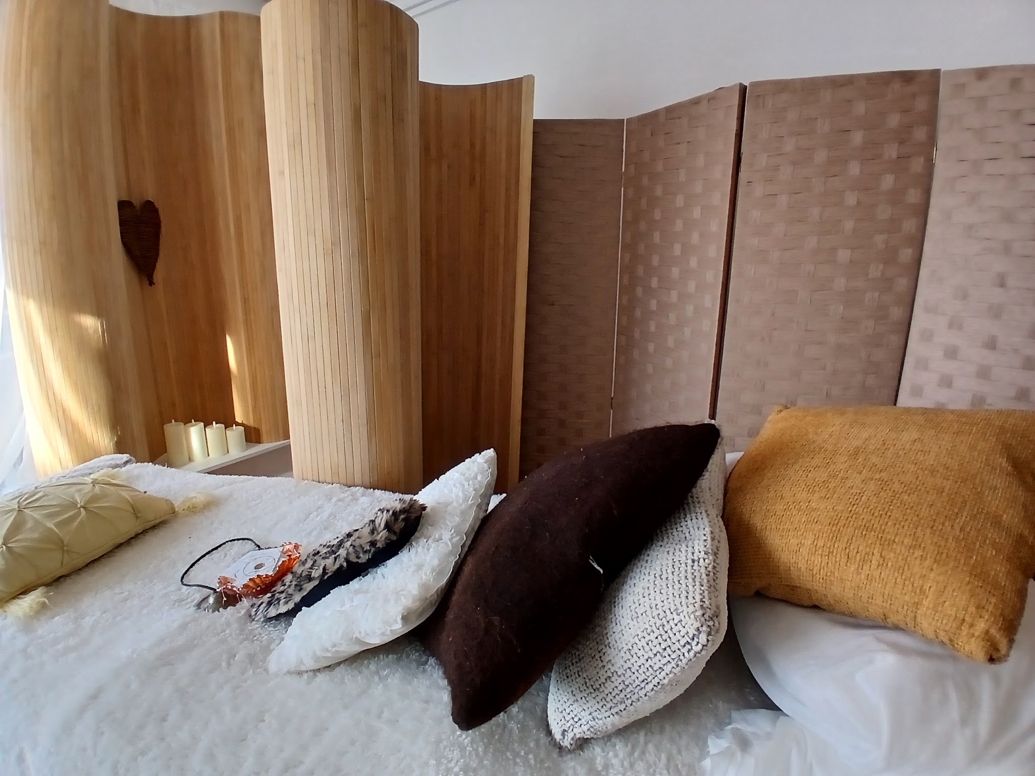 The couch with cushions and an eye mask in front of bamboo screens
