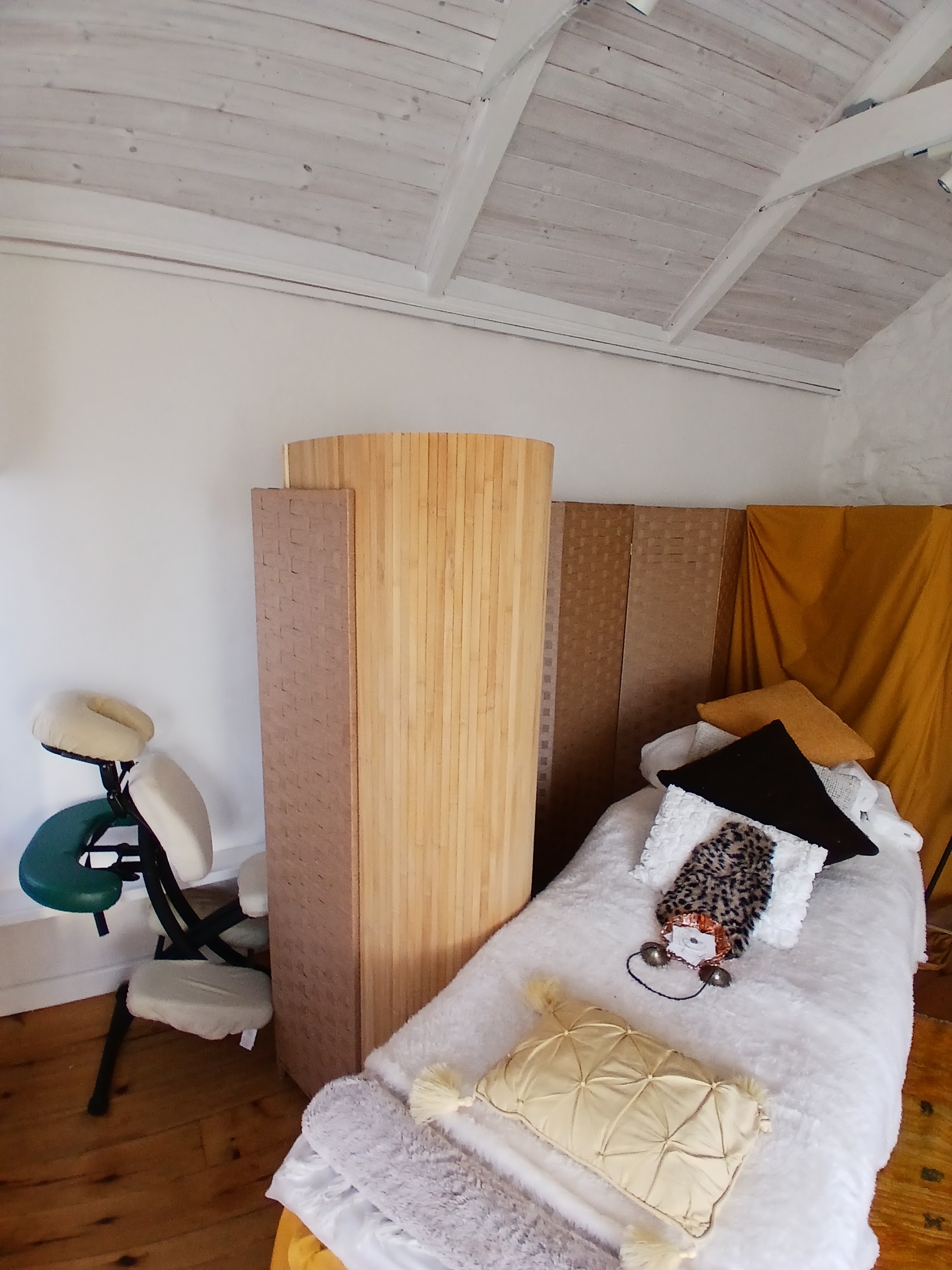 The treatment room under its high white timber ceiling, with the couch, screens and massage chair
