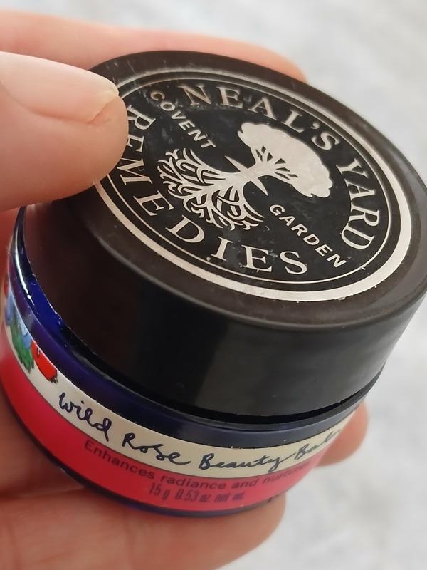 A jar of Neal's Yard Remedies Wild Rose Beauty Balm held in the hand