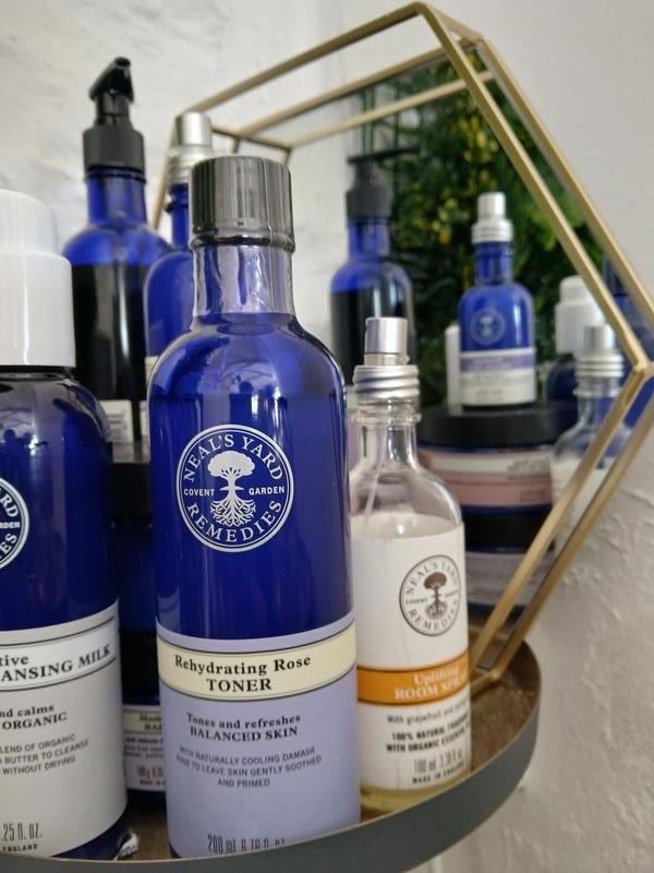 Neal's Yard Remedies cleansing milk and rose toner bottles on a brass stand