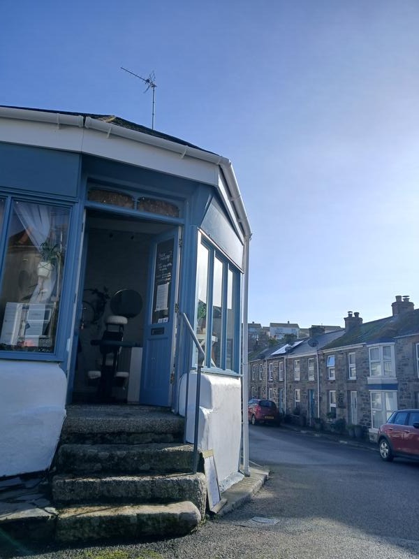 The blue porch and stone steps up to the treatment room on a Porthleven street